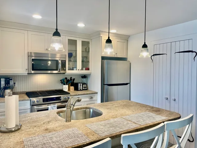 a kitchen with stainless steel appliances granite countertop a refrigerator a sink and a stove