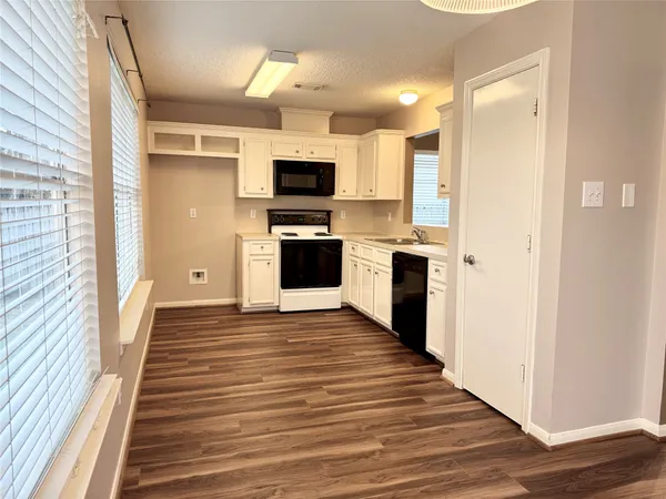 a view of a kitchen with wooden floor and electronic appliances