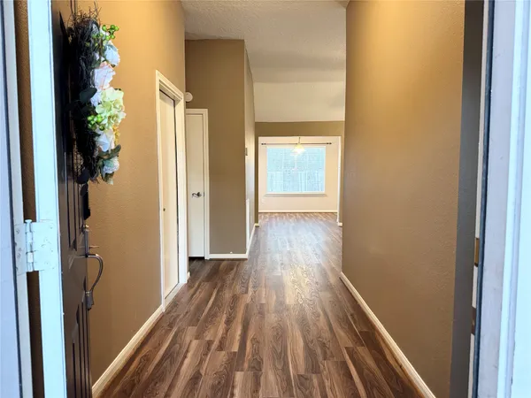 a view of a hallway with wooden floor and a bathroom