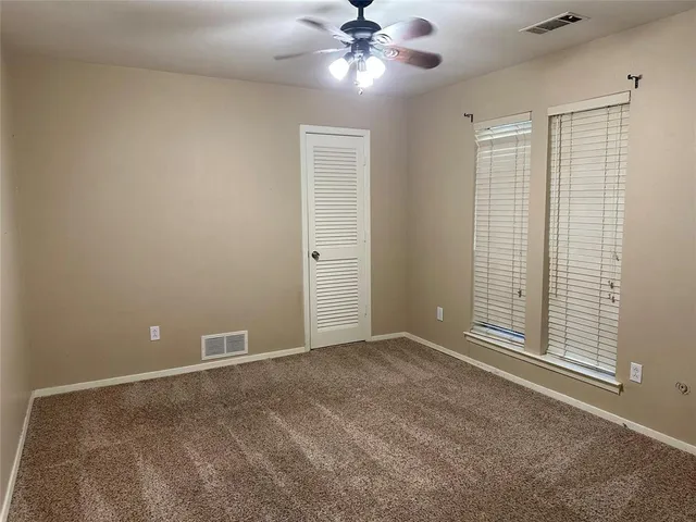 a view of an empty room with a ceiling fan and window