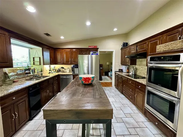 a kitchen with stainless steel appliances granite countertop a stove refrigerator sink and cabinets