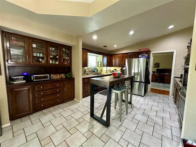 a kitchen with stainless steel appliances kitchen island granite countertop a refrigerator and a stove top oven