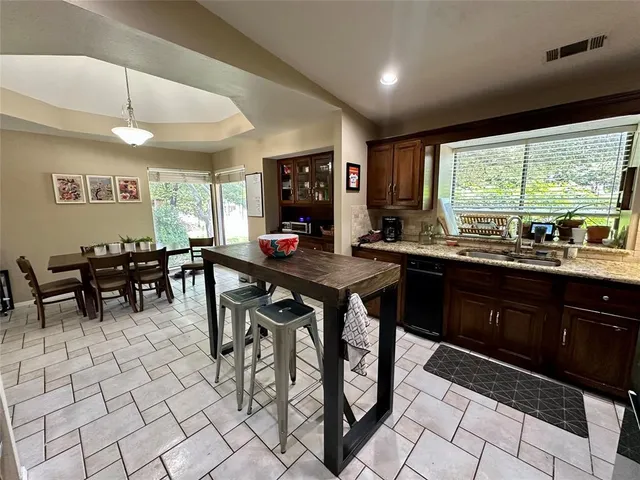 a kitchen with stainless steel appliances granite countertop table chairs sink and cabinets