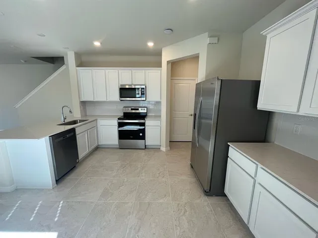 a kitchen with stainless steel appliances a refrigerator and a stove top oven