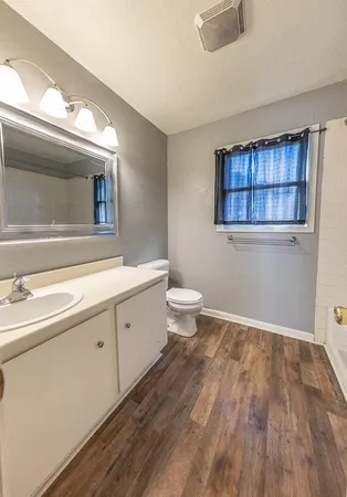 a spacious bathroom with a granite countertop sink toilet and a mirror