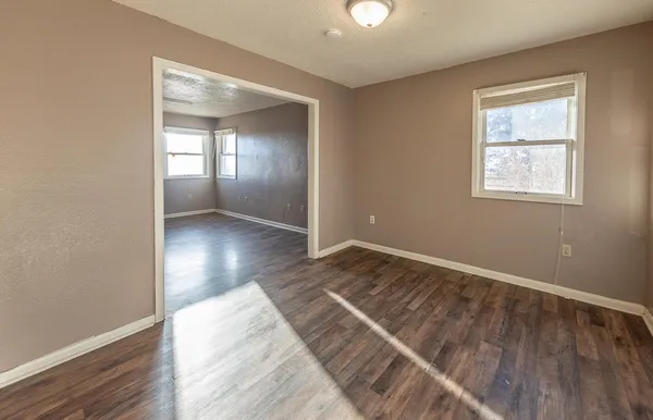 an empty room with wooden floor and windows