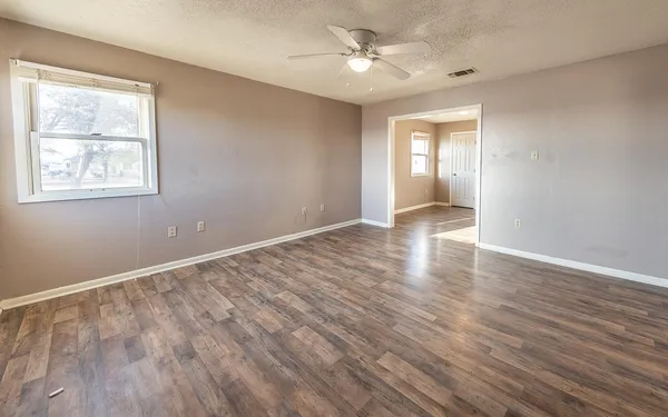 a view of an empty room with a window and wooden floor