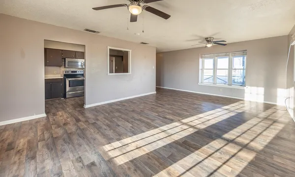 a view of empty room with wooden floor and ceiling fan