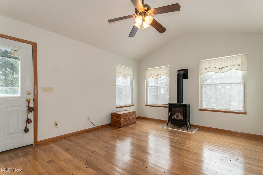 3303 River Road Perry, OH 44081 - Photo 6 of 34 Unfurnished living room featuring vaulted ceiling, a wood stove, a wealth of natural light, and light hardwood / wood-style flooring