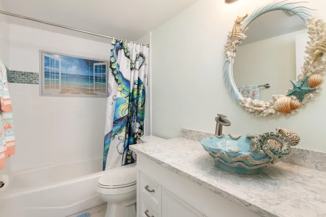 a bathroom with a granite countertop sink a toilet and shower