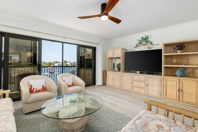 a living room with furniture a flat screen tv and a floor to ceiling window