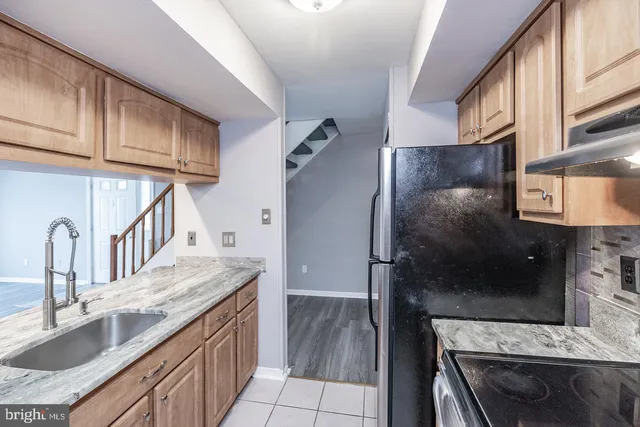 a kitchen with granite countertop a sink stove and refrigerator