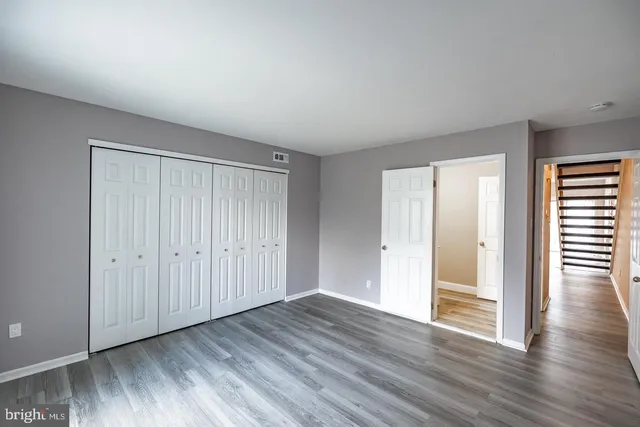 a view of an empty room with wooden floor and windows