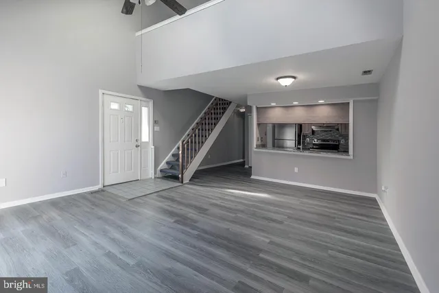 an empty room with wooden floor staircase and windows