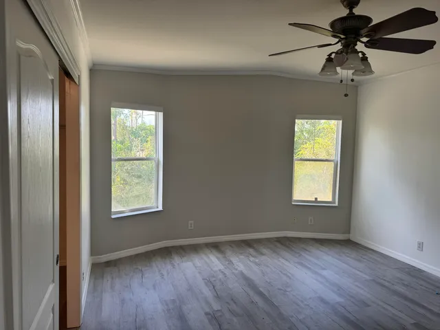 a view of an empty room with a window and wooden floor