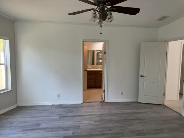 an empty room with wooden floor chandelier fan and windows