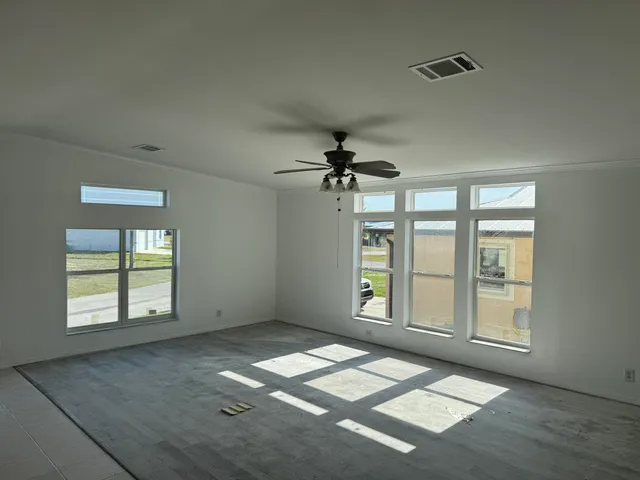 an empty room with windows and ceiling fan