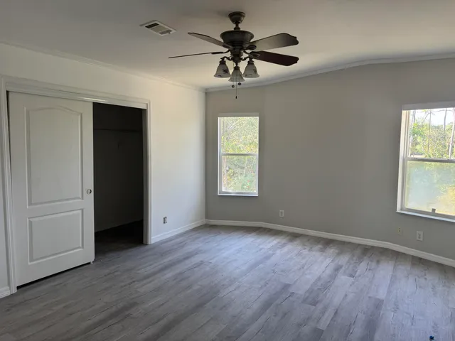 a view of an empty room with a window and wooden floor