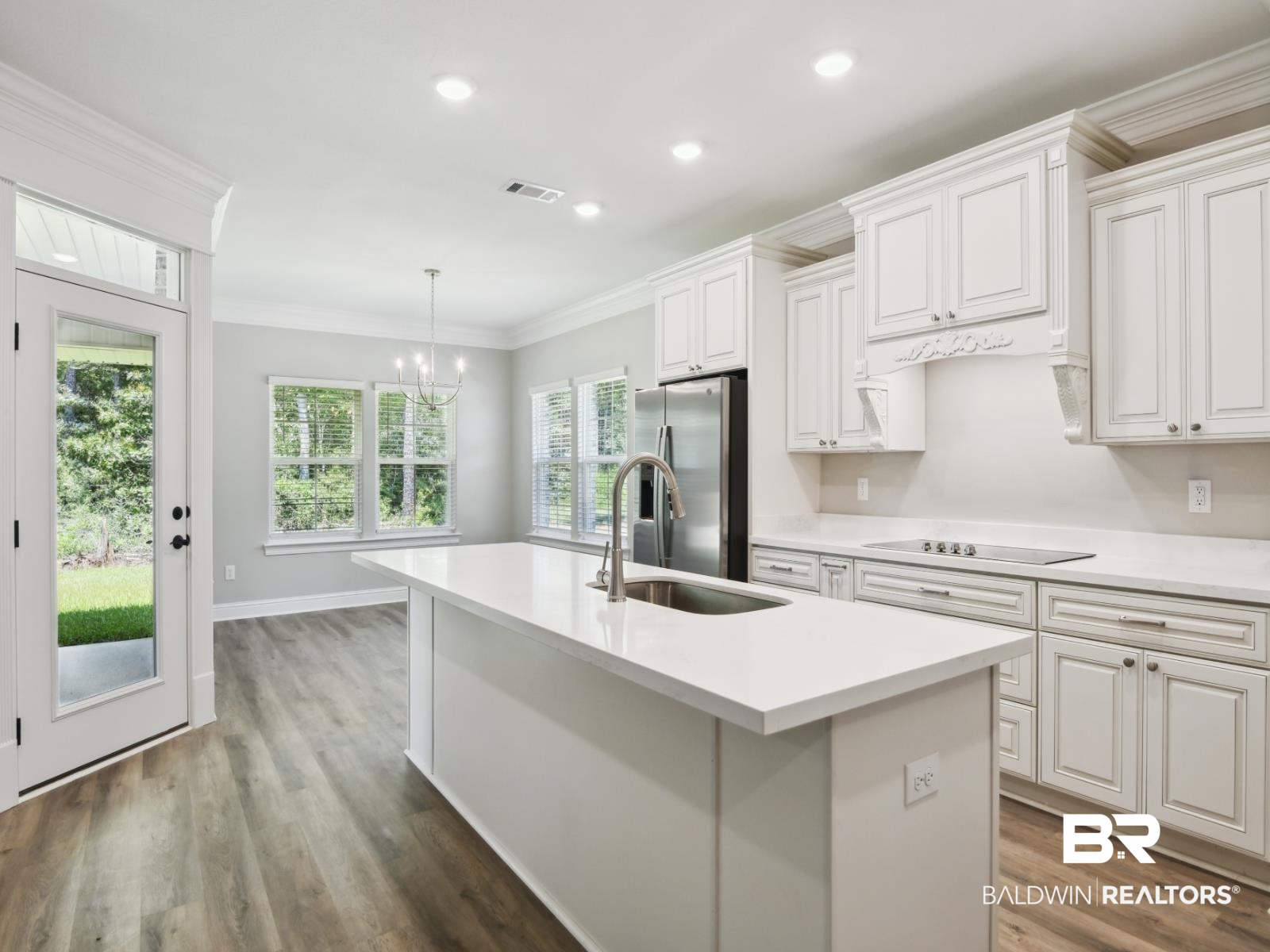 23937 Peppermint Street Elberta, AL 36530 - Photo 3 of 22 Kitchen with crown molding, wood finished floors, a kitchen island with sink, light countertops, and recessed lighting