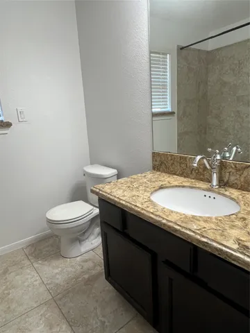 a bathroom with a granite countertop sink a toilet and a mirror