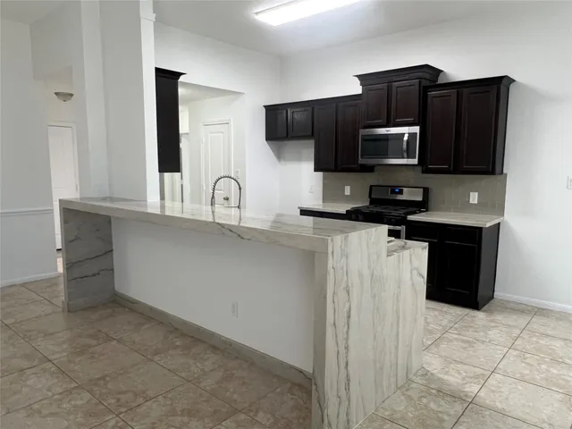 a kitchen with granite countertop a refrigerator and a stove top oven
