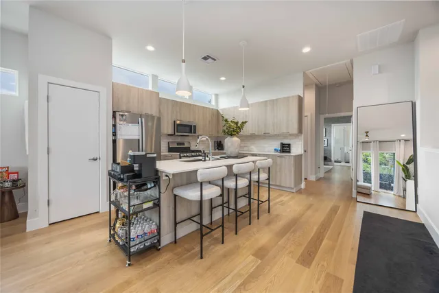 a kitchen with stainless steel appliances kitchen island granite countertop a table chairs sink and cabinets