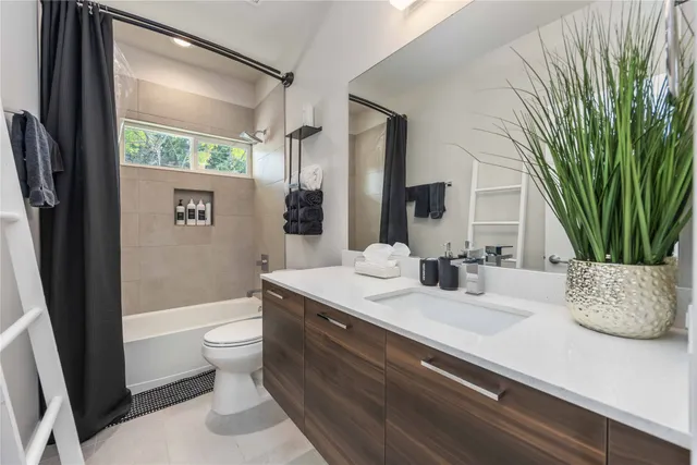 a bathroom with a granite countertop sink a toilet a mirror and shower