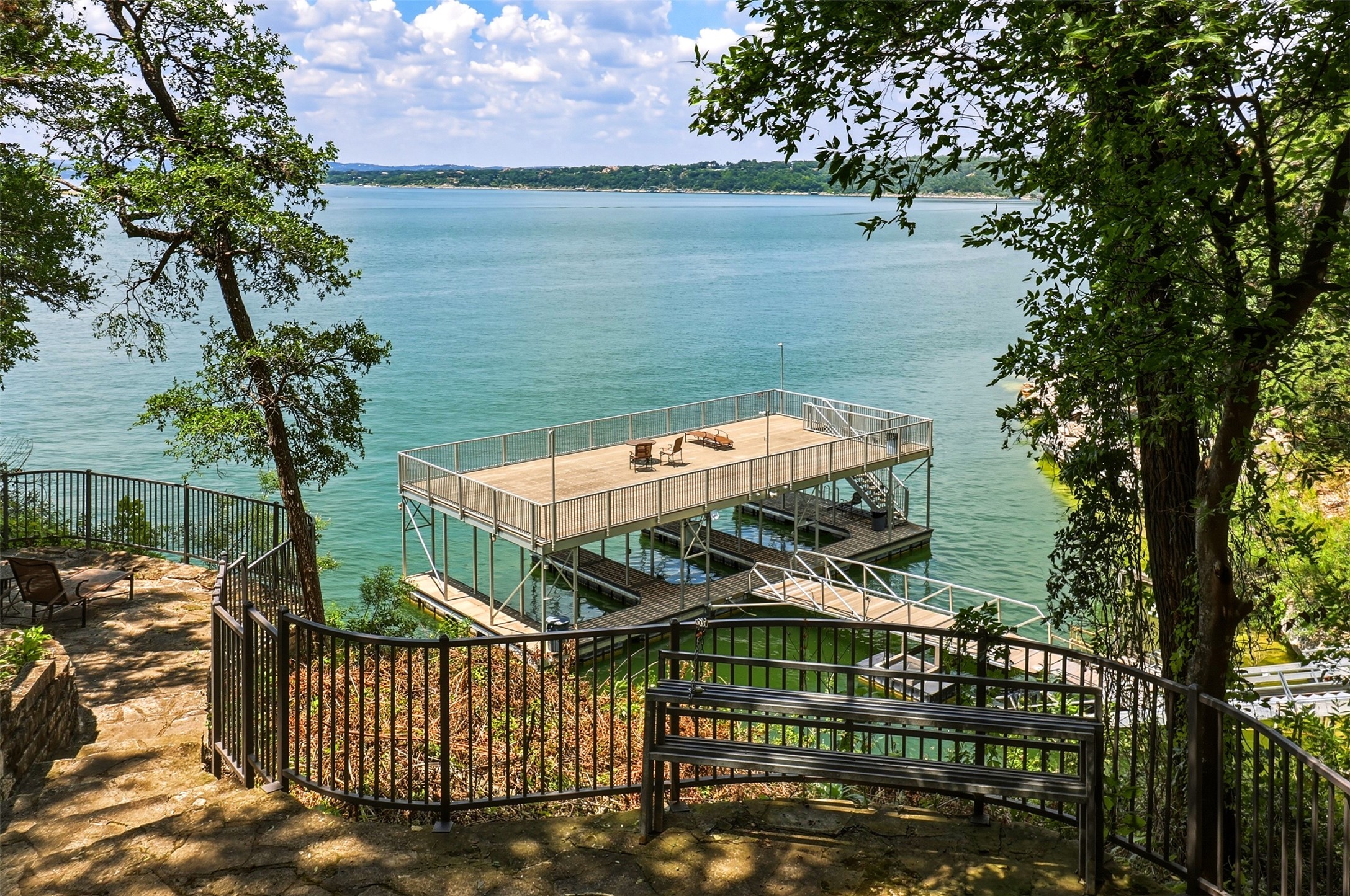 2918 Ranch Road 620, Unit 265 Austin, TX 78734 - Photo 35 of 40 A private, multi-level boat dock extends into a pristine lake, framed by lush trees and a winding stone pathway.