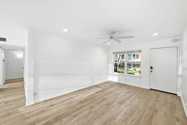 a view of an empty room with wooden floor and windows