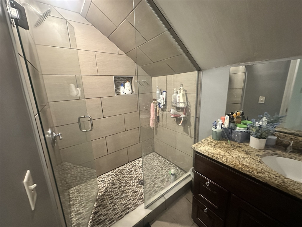 33 Iroquois Street, Unit 2 Boston, MA 02120 - Photo 10 of 14 a bathroom with a granite countertop shower a sink and a mirror