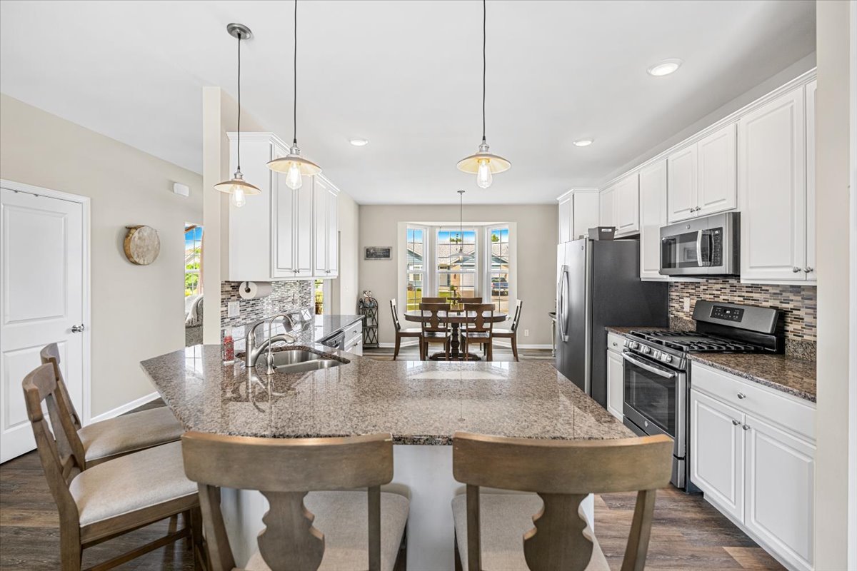 2220 Tyler Trail McHenry, IL 60051 - Photo 4 of 24 a kitchen with stainless steel appliances granite countertop a dining table chairs refrigerator and microwave