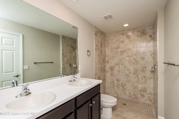 a bathroom with a sink a toilet a mirror and shower