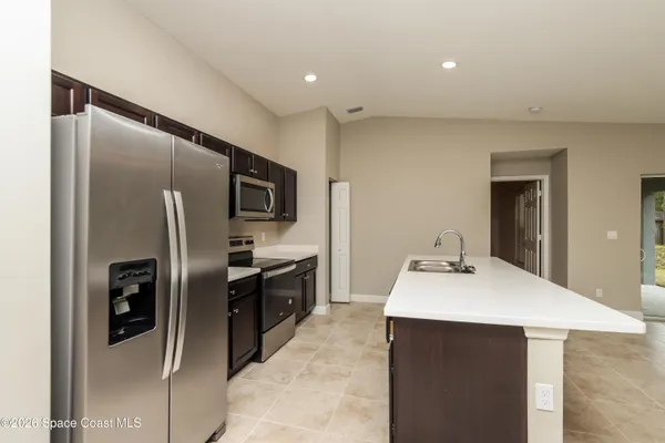 a kitchen with stainless steel appliances kitchen island granite countertop a refrigerator and a sink