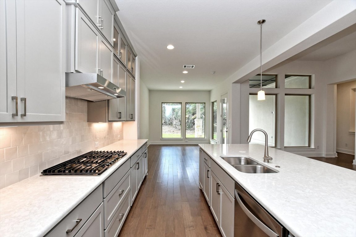 4828 Destination Way Jonestown, TX 78645 - Photo 11 of 33 a kitchen with stainless steel appliances a sink stove and cabinets