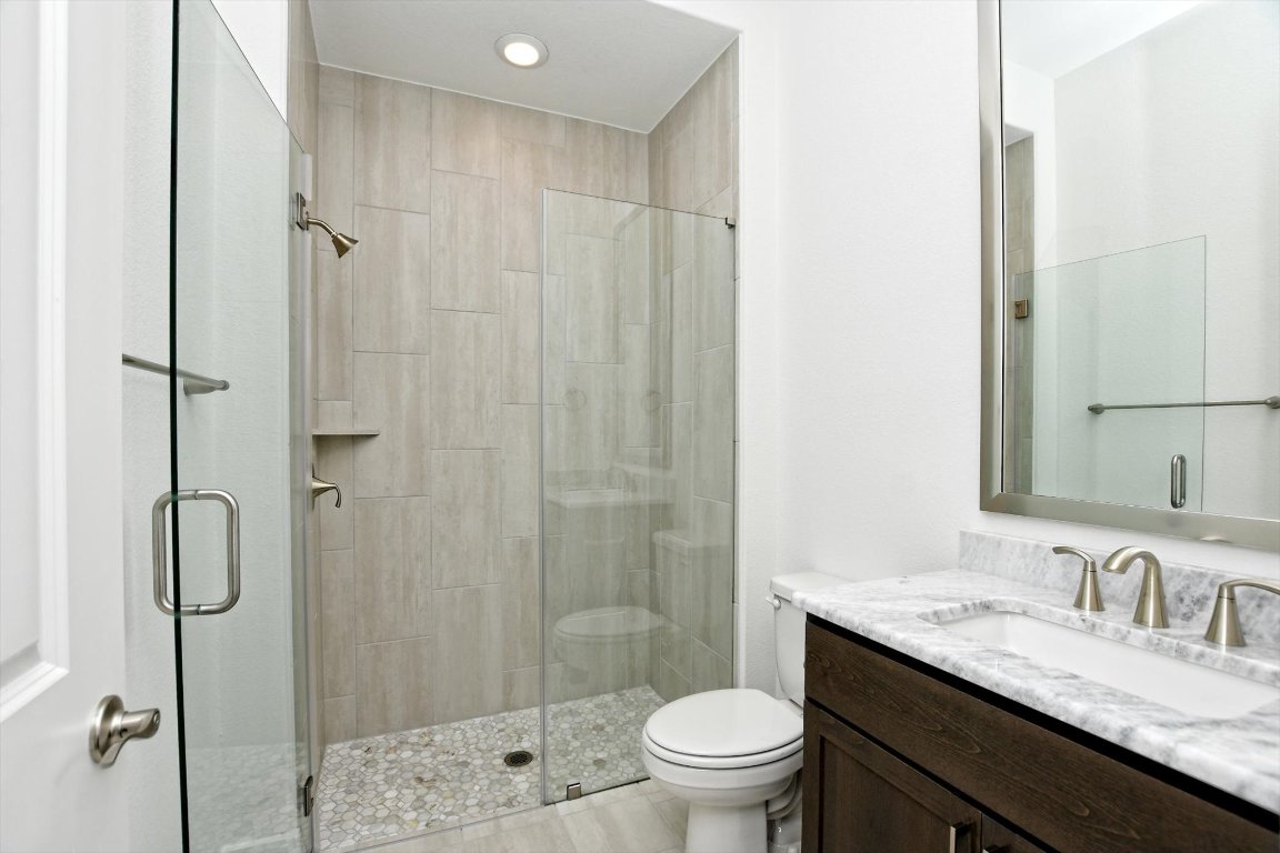 4828 Destination Way Jonestown, TX 78645 - Photo 23 of 33 a bathroom with a granite countertop sink toilet and shower