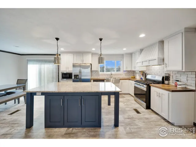 a kitchen with stainless steel appliances kitchen island granite countertop a table chairs sink and cabinets