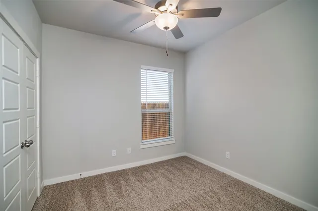 an empty room with windows and chandelier fan