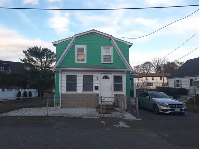 a front view of a house with cars parked on road