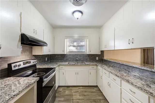 a kitchen with granite countertop a sink a stove and cabinets