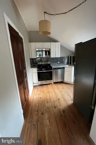 a kitchen with stainless steel appliances a stove refrigerator and wooden floor