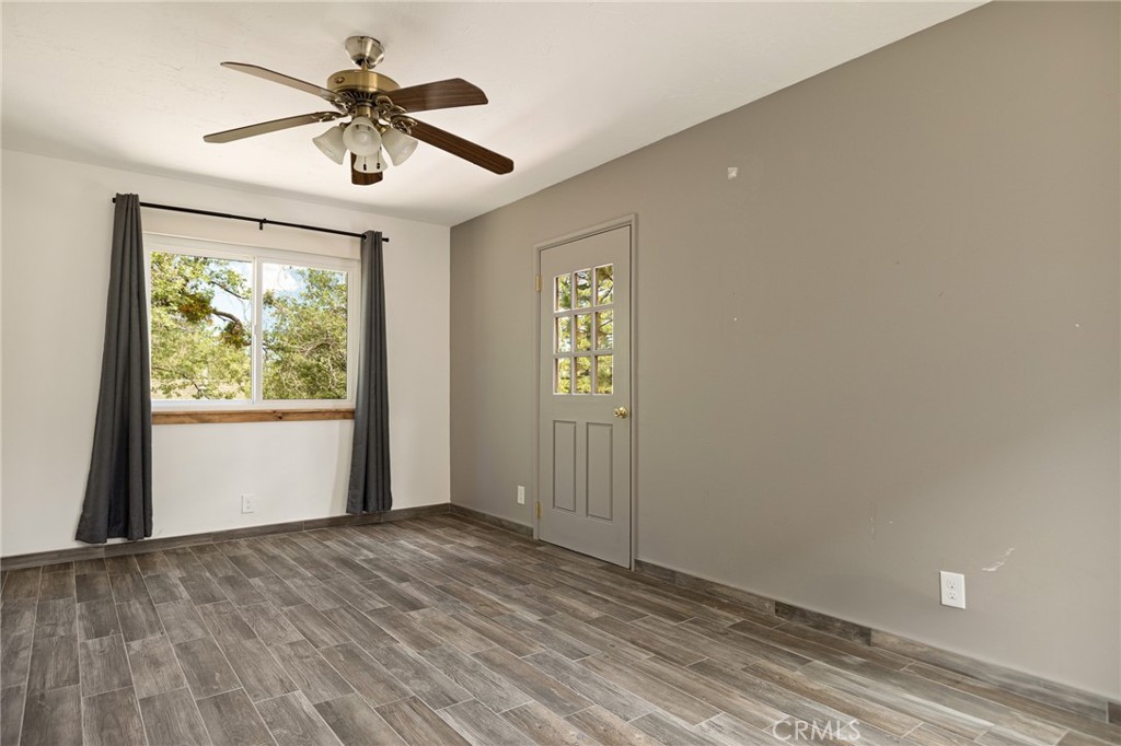 33159 Ridge Drive Running Springs, CA 92382 - Photo 16 of 24 an empty room with wooden floor chandelier fan and windows