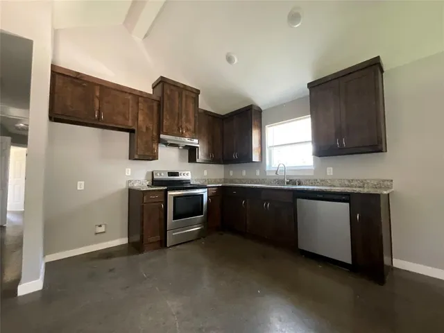a kitchen with stainless steel appliances granite countertop a stove a sink and a refrigerator