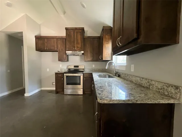 a kitchen with stainless steel appliances granite countertop a sink stove and refrigerator