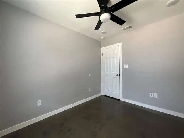 an empty room with a fan & a ceiling fan