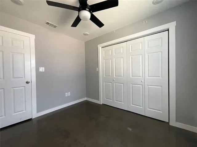 an empty room with ceiling fan and windows