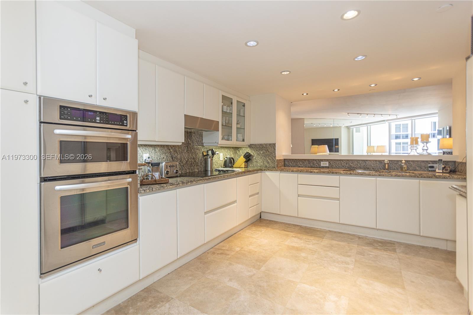 9559 Collins Avenue, Unit S7D Surfside, FL 33154 - Photo 21 of 59 a kitchen with stainless steel appliances granite countertop a stove and white cabinets