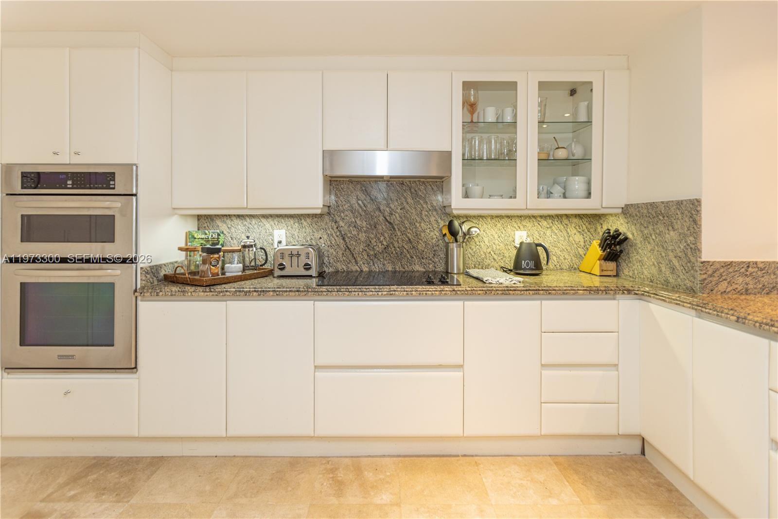 9559 Collins Avenue, Unit S7D Surfside, FL 33154 - Photo 24 of 59 a kitchen with granite countertop white cabinets and stainless steel appliances