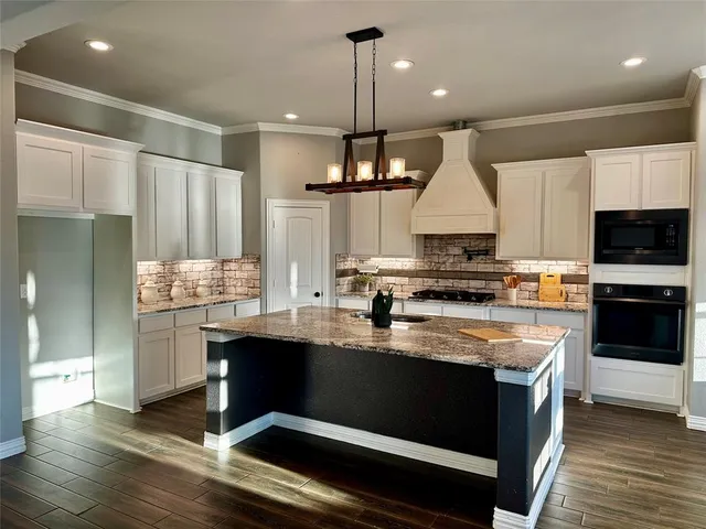 a kitchen with granite countertop a sink a stove and cabinets