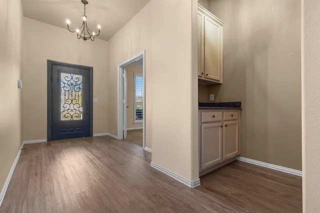 a view of a hallway with wooden floor and a kitchen