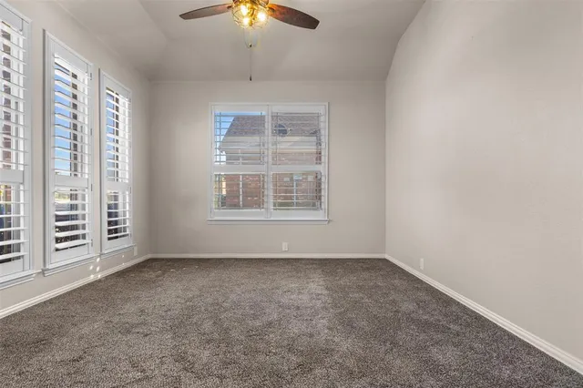 an empty room with windows and chandelier fan